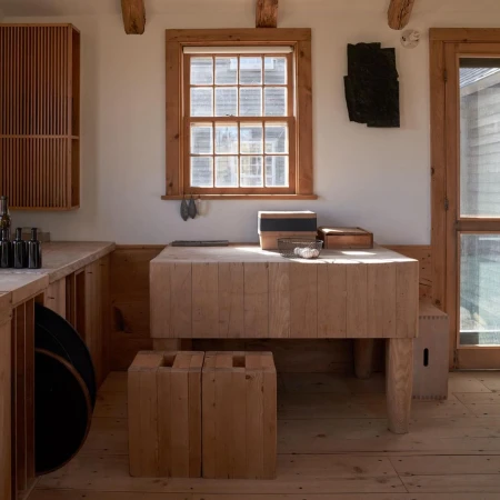 Interior featuring a wooden table with boxes and shells, complemented by rustic wood floors, cabinetry, and a sunlit window.