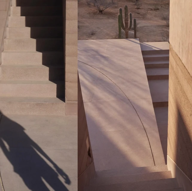 Minimalist architecture featuring tan-colored stairs and walls, complemented by the silhouette of a person and sparse desert vegetation.