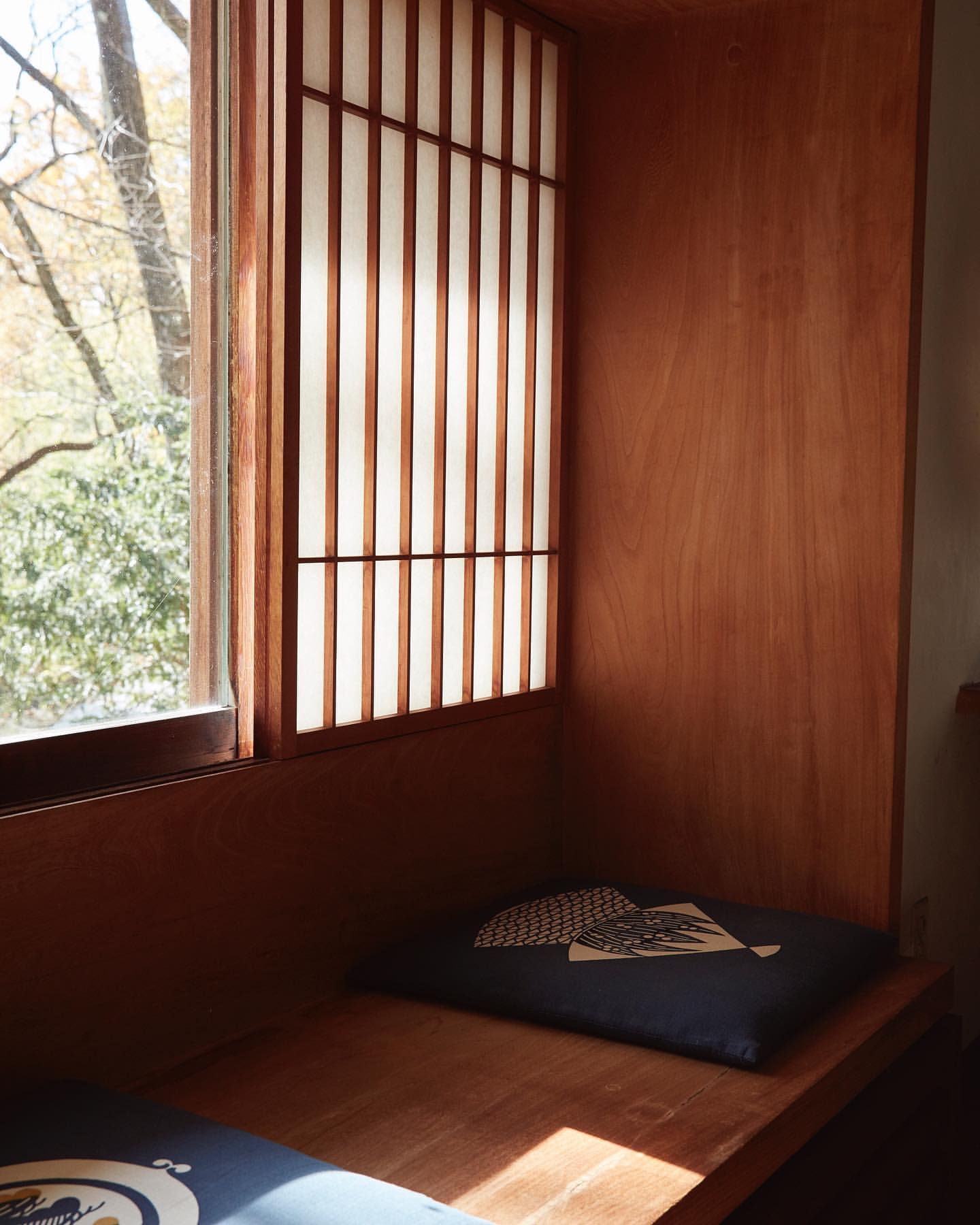 Indoor view features a wooden alcove with window, Japanese paper screen, seat cushion, wooden bench, and natural daylight.