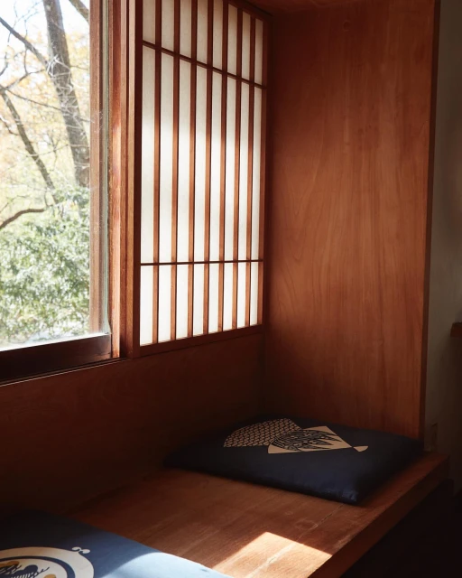 Indoor view features a wooden alcove with window, Japanese paper screen, seat cushion, wooden bench, and natural daylight.