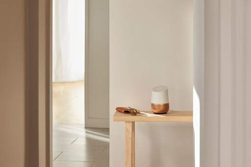 Smart home speaker on a wooden console table in a minimalist interior setting with keys and wallet, highlighting domestic technology.