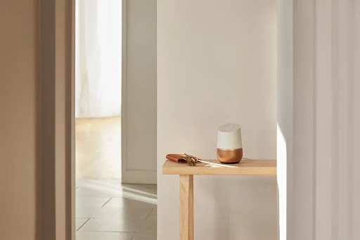 Smart home speaker on a wooden console table in a minimalist interior setting with keys and wallet, highlighting domestic technology.