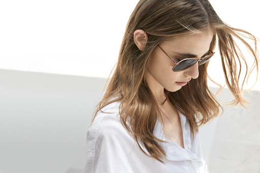 Woman wearing sunglasses and a white shirt against a white background by Martien Mulder