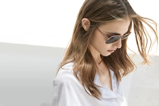 Woman wearing sunglasses and a white shirt against a white background by Martien Mulder