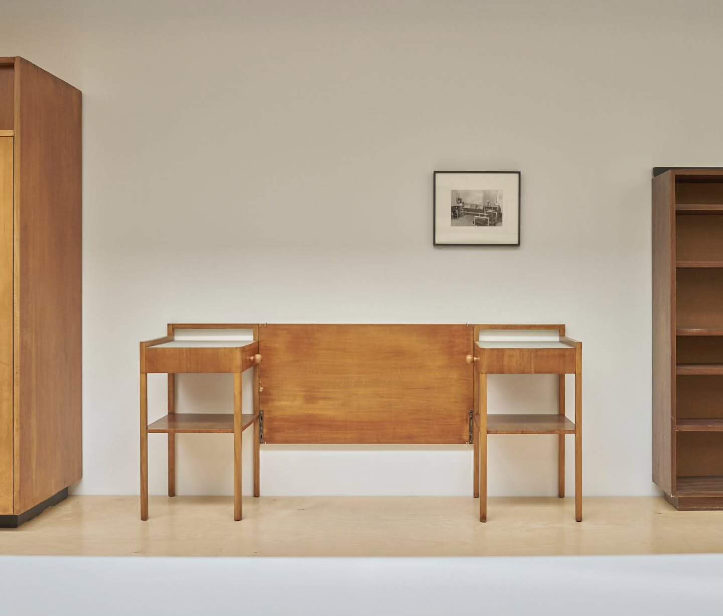 Interior view of vintage mid-century modern bedroom set, featuring headboard, nightstands, wardrobe, and bookcase in a minimal setting.