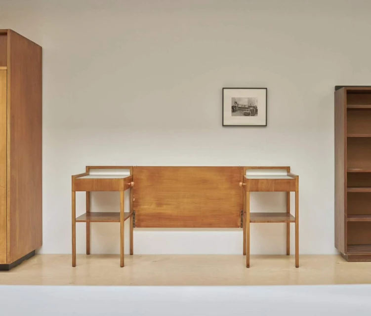 Interior view of vintage mid-century modern bedroom set, featuring headboard, nightstands, wardrobe, and bookcase in a minimal setting.