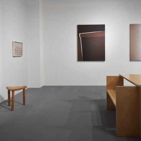 Minimalist art gallery interior featuring geometric abstract paintings in shades of brown and gray with wooden furniture. Modern aesthetic.