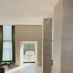 Interior architectural shot featuring travertine stone pillars, a central doorway looking out to a courtyard with a fire feature