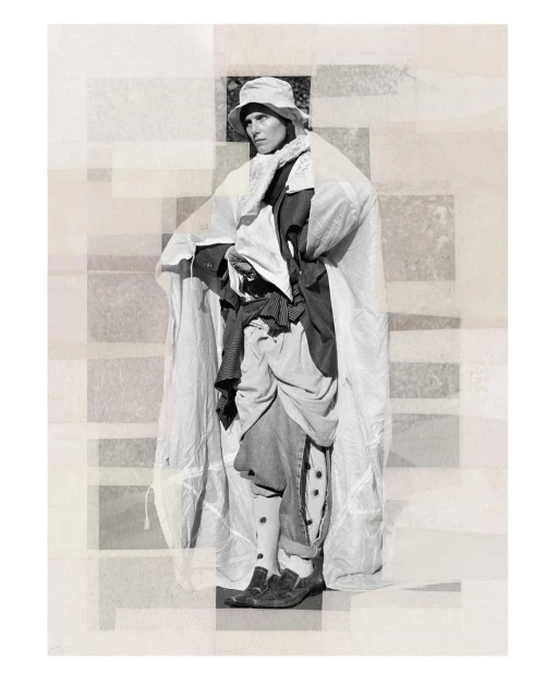 Monochrome fashion shot of a person wearing a bucket hat and draped in white fabric, standing against a geometric backdrop.
