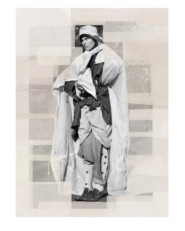 Monochrome fashion shot of a person wearing a bucket hat and draped in white fabric, standing against a geometric backdrop.