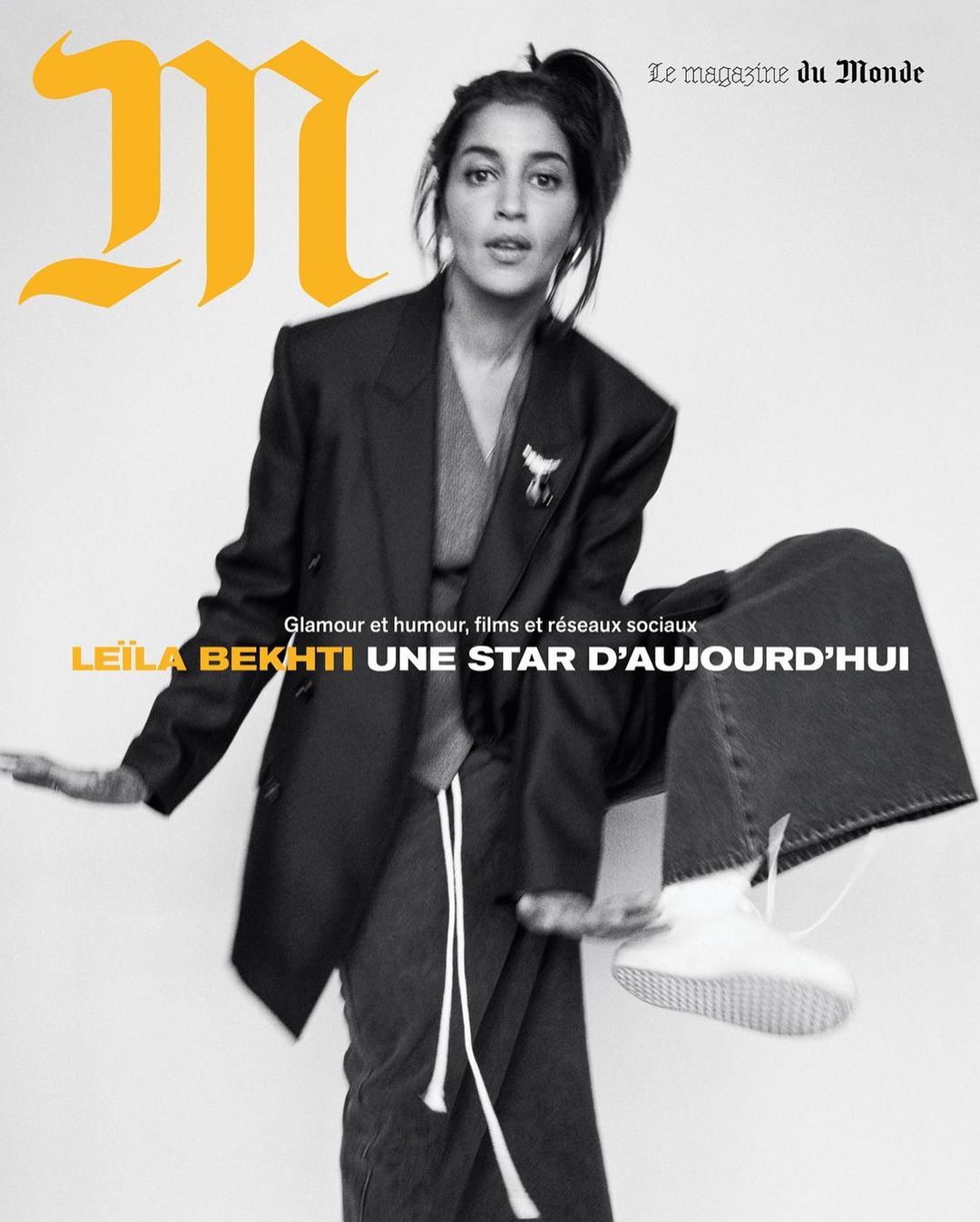 Magazine cover featuring Leila Bekhti in a black blazer, grey top and pants, and white sneakers against a bright background.