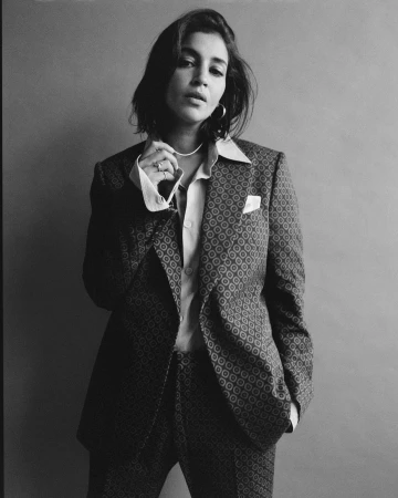 Black and white portrait of a woman with dark hair wearing a patterned suit jacket and collared shirt against a plain background