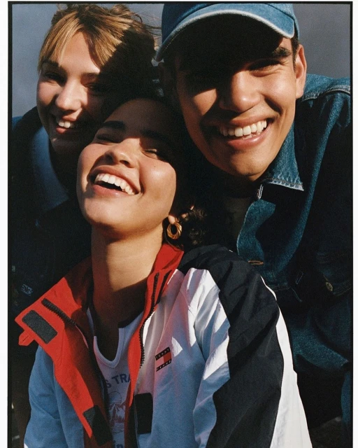 Close-up of three smiling people with a fair complexion, dark hair, and casual attire, enjoying the daylight, with shallow depth of field.