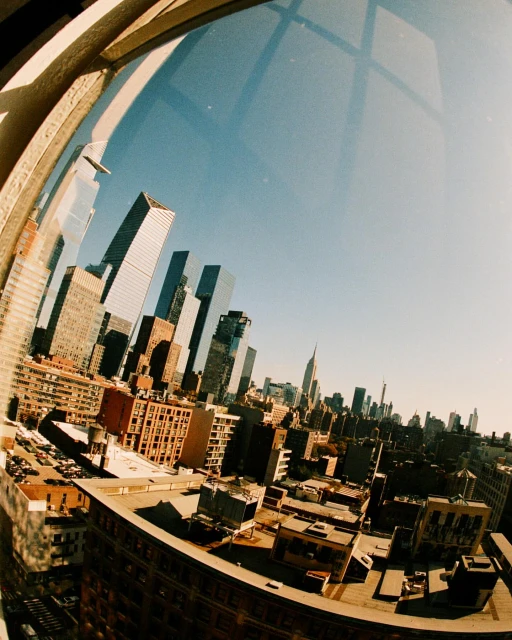 Wide angle shot of the New York City skyline showing numerous tall buildings and skyscrapers under a clear blue sky on a sunny day.