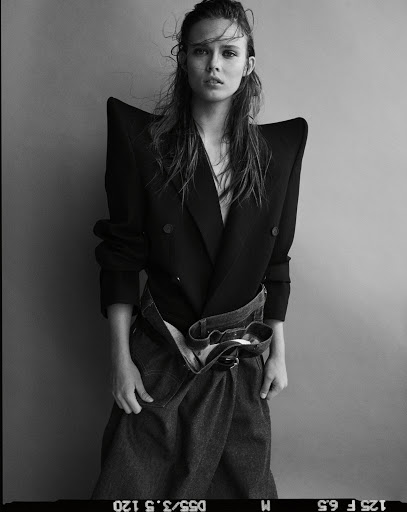 Black and white portrait of a model wearing a structured sharp-shouldered jacket and denim skirt by photographer Matteo Montanari.