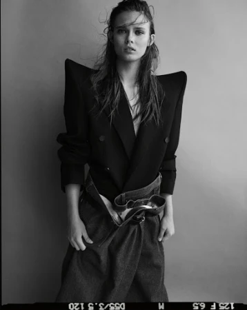 Black and white portrait of a model wearing a structured sharp-shouldered jacket and denim skirt by photographer Matteo Montanari.