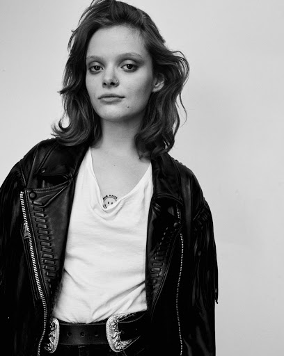 Monochrome portrait of a young woman in a black leather jacket and white t shirt against a plain background