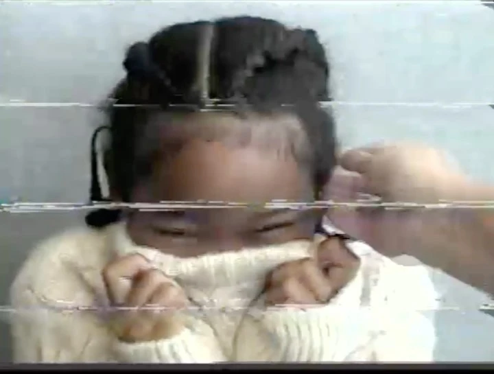 Close-up of a child in a cream-colored knit sweater, partially covering their face, with an adult hand near the child's face.