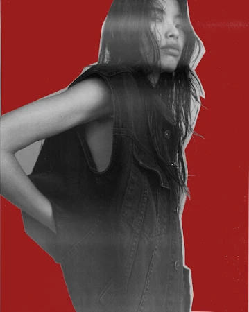 Monochrome fashion shot of an adult woman in a denim vest with a red background. Close-up on the female adult's chest and shoulder area.