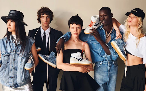 Group of five fashion models showcasing sneakers; diverse ensemble with various denim, black and white clothing, and hats in a studio setting.