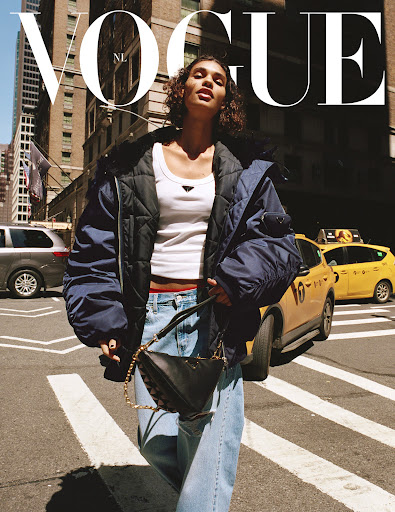 Vogue magazine cover featuring a woman in an oversized puffer jacket and jeans walking across a crosswalk in an urban environment.