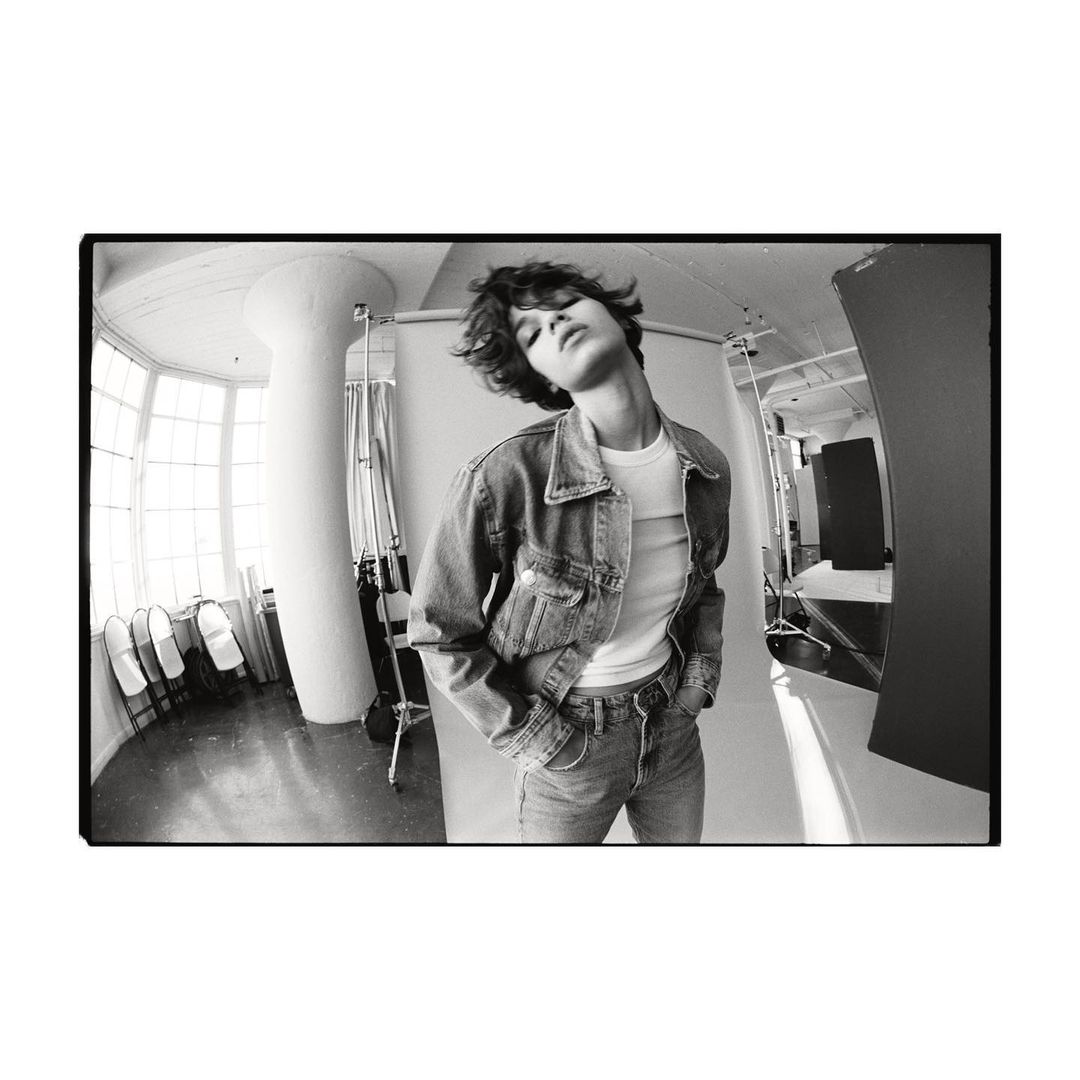 Model with dark short hair wearing a denim jacket and jeans in a photo studio by photographer Matteo Montanari.
