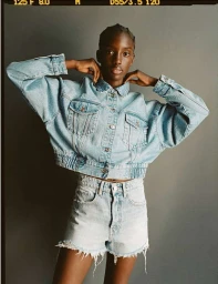 Model in light wash denim jacket and matching shorts posing against a grey studio wall by photographer Matteo Montanari