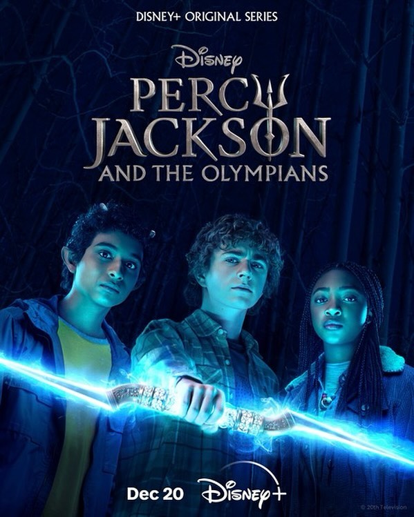 Promotional image of the Disney+ series Percy Jackson and the Olympians features three young actors holding a glowing blue object in a dark forest.
