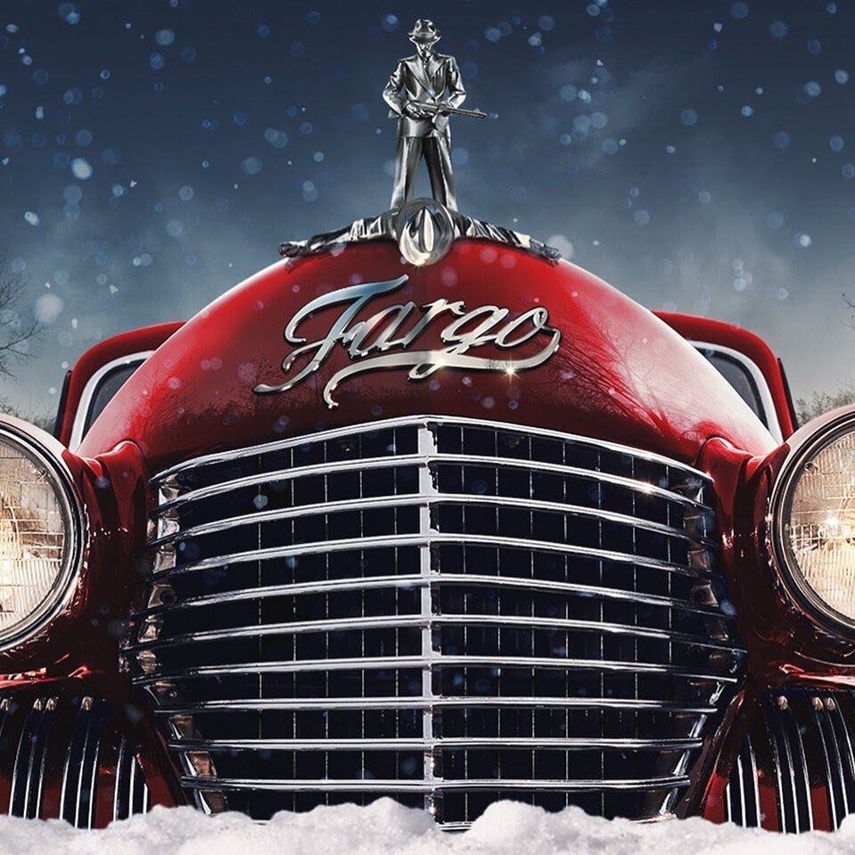 Red vintage car in snow with statue of man holding rifle. Sign reads Fargo. Moody winter scene with dark blue sky and blurred trees.