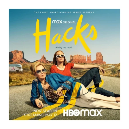 Poster for the HBO Max series Hacks featuring Jean Smart and Hannah Einbinder on a highway with desert mountains and an approaching bus.