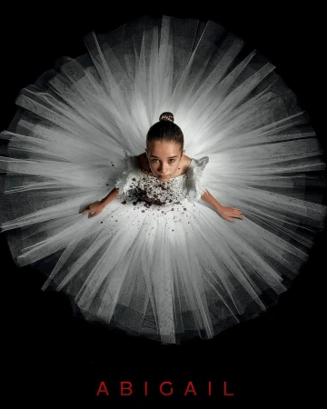 Eye-level shot of a young girl in a white tutu with brown accents against a black backdrop, looking up at the camera with a serious expression.