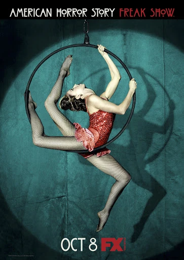 Woman in red sequin leotard and fishnet stockings suspended in aerial hoop, performing for American Horror Story: Freak Show promo.