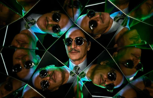 Kaleidoscopic mirrored reflection of a bald man wearing dark sunglasses, patterned tie, and suit photographed by Matthias Clamer.
