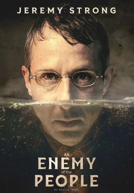 Book cover featuring Jeremy Strong partially submerged in water, wearing glasses. The title 'An Enemy of the People' is displayed.