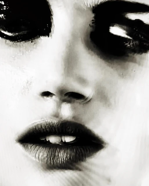 Close-up artistic portrait of an adult female with striking black eye makeup, dark lipstick, and a pale skin tone, creating a dramatic look.