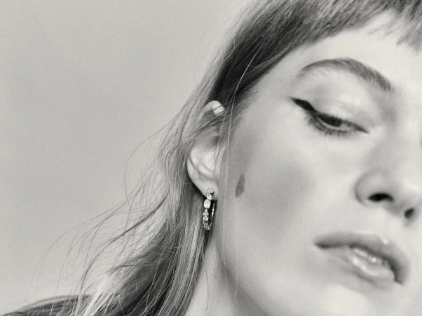 Close up monochrome portrait of a woman wearing diamond hoop earrings and winged eyeliner by Melanie and Ramon.