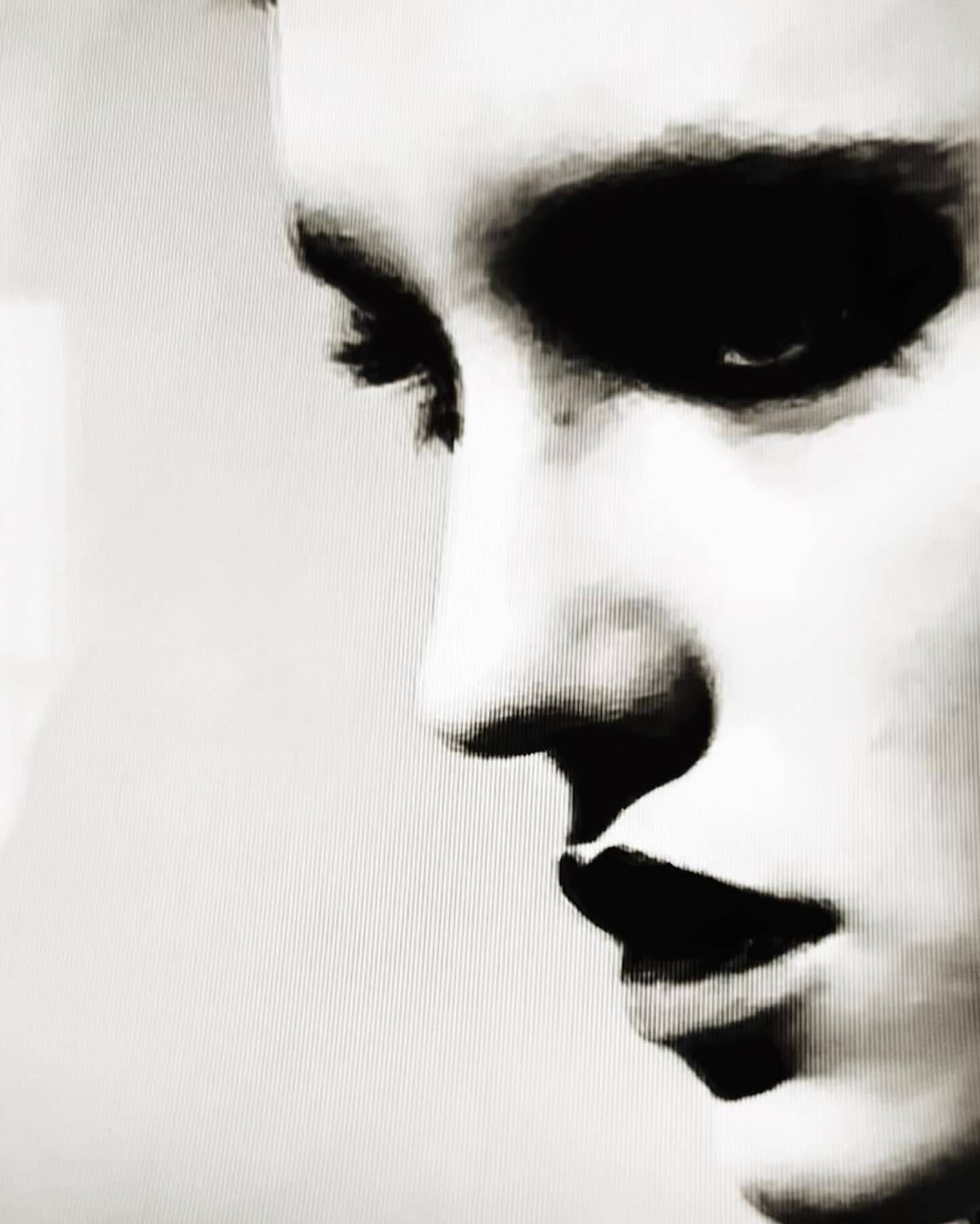 Close-up monochrome portrait of a person profile featuring high-contrast dark eye makeup and heavy grain texture.
