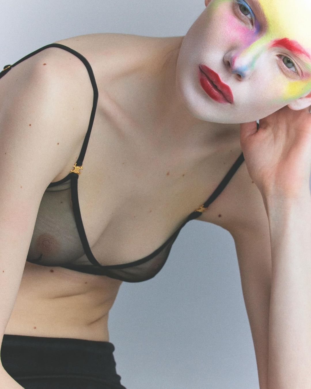 Close-up studio shot of a fair-skinned woman with artistic makeup wearing a black bra, creating a visually striking and intimate aesthetic.