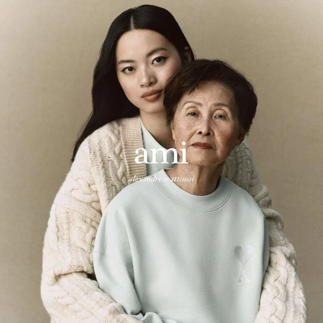 Two women of Asian descent pose indoors for a fashion campaign, showcasing a cream cardigan and a light blue sweatshirt against a beige backdrop.
