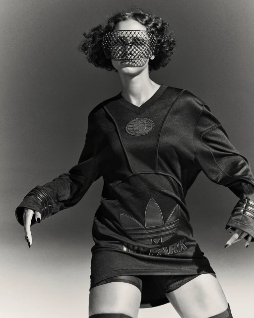 Monochrome portrait of a curly-haired model wearing an Adidas x Ivy Park outfit and face covering, posing against a plain backdrop.