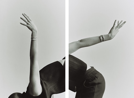 Monochrome shot of a model wearing a bangle with arms raised against a white background creating a mirrored effect.