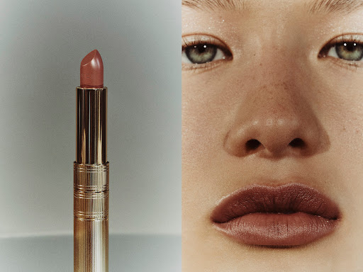Close-up split image showing a metallic gold lipstick tube next to a person's face wearing matching lipstick and subtle eye makeup.
