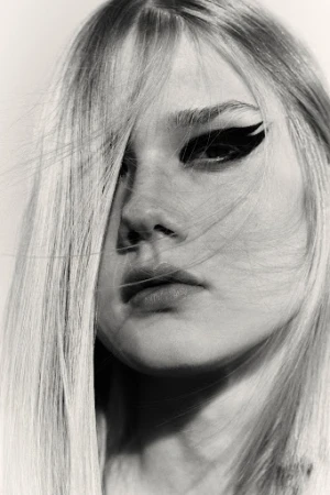 Close-up portrait of a woman with long blonde hair and dramatic black winged eyeliner by Melanie and Ramon.