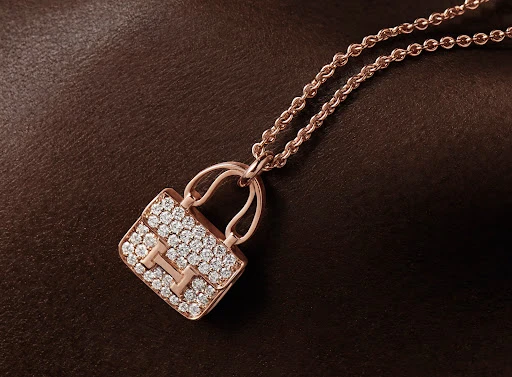 Rose gold handbag pendant necklace paved with diamonds on a dark textured brown leather background