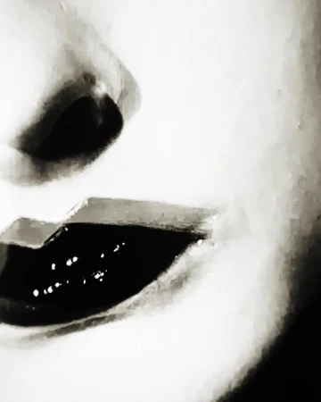 Extreme close-up macro portrait of a person face focusing on dark glossy lips and nose in monochrome grain