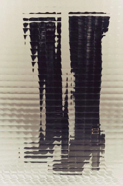 Graphic image of a pair of dark-colored, shiny boots with buckle detail, presented in a horizontally-striped, abstract, and somewhat blurred style.