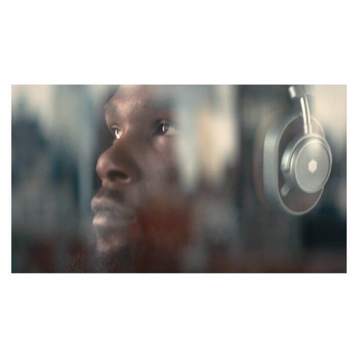 Profile of an adult male of African descent wearing headphones, side view, slightly diffused by an overlay in an indoor environment.