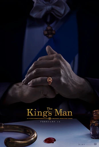 Movie poster still for The King's Man with a gloved person's hands folded, a golden signet ring, paper and inkwell on the desk.