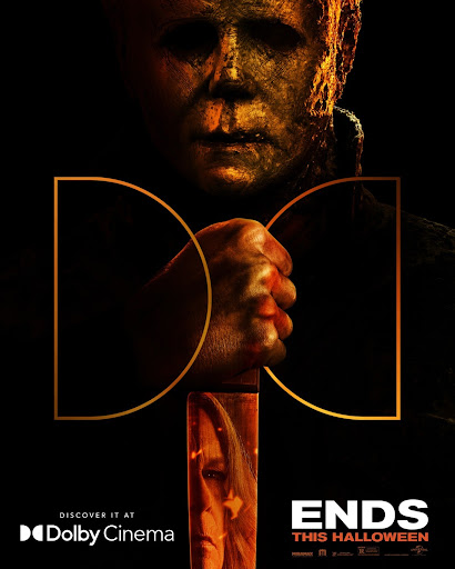 Close-up poster of Michael Myers holding a knife with a reflection of a woman's face on the blade against a dark background
