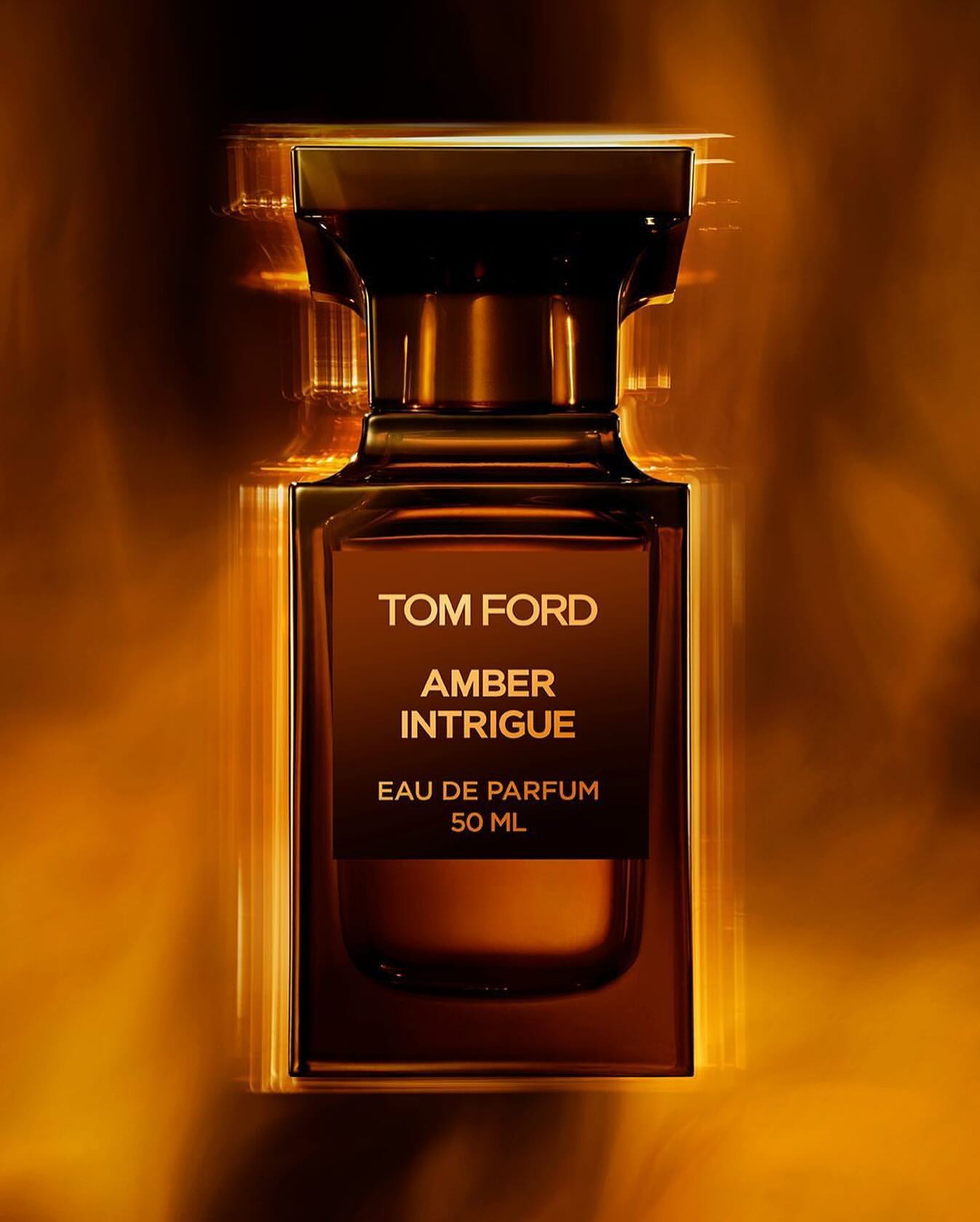 Tom Ford Amber Intrigue perfume bottle in a square shape with amber coloring, displayed against a softly blurred amber background.